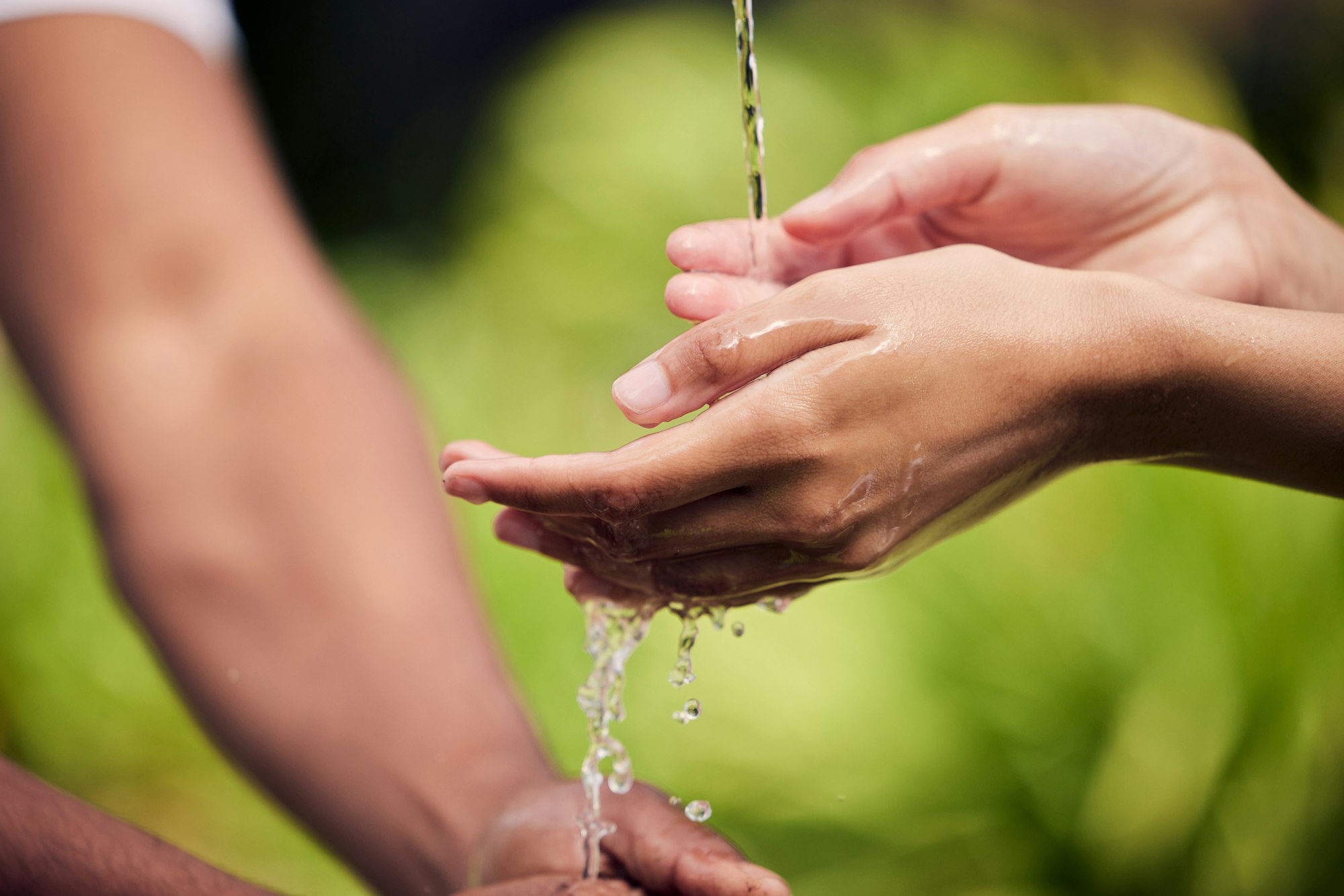 To see tomorrow, save today. Shot of unrecognisable people ringing their hands with water outside.