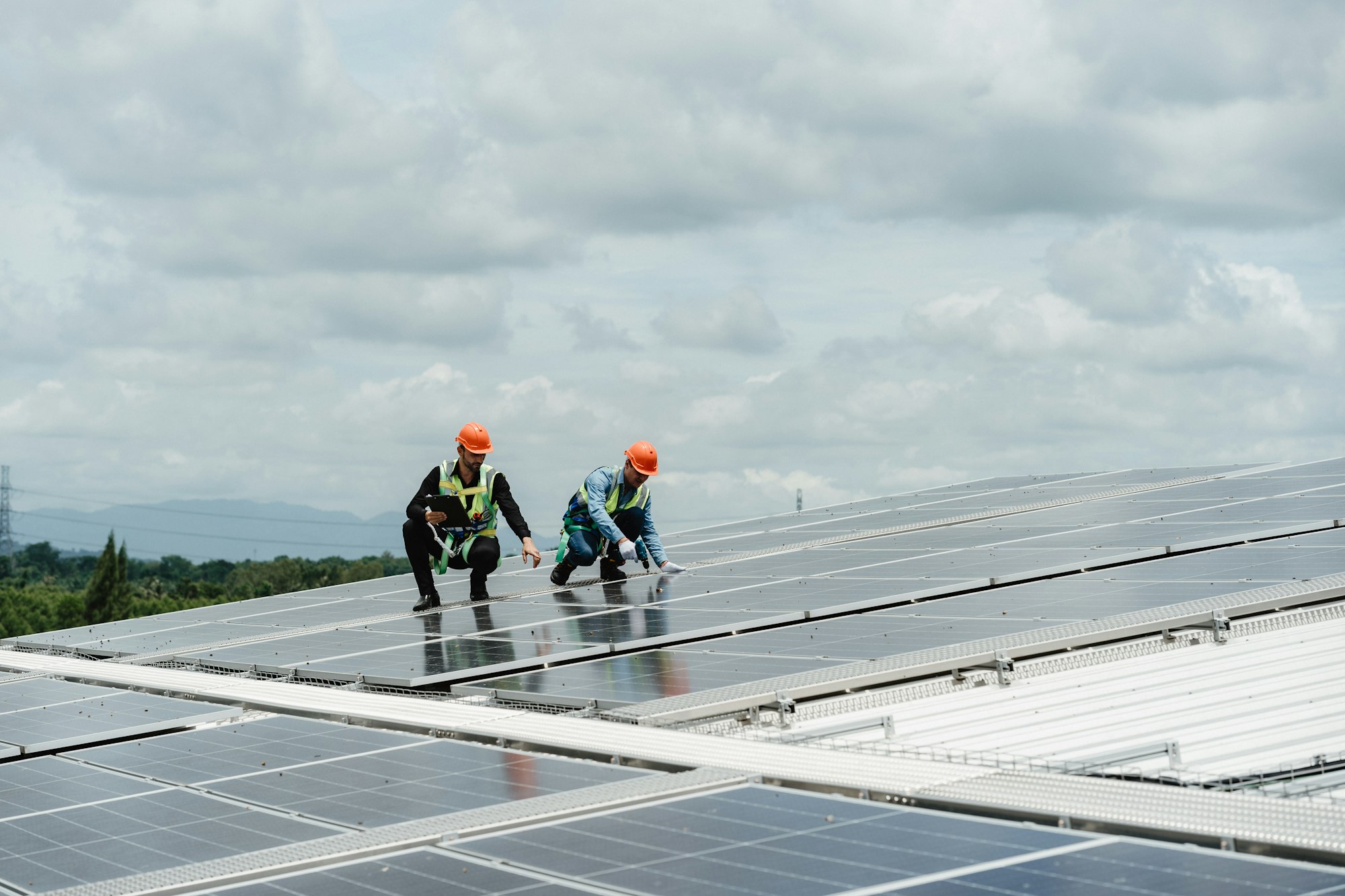 Two young engineer and inspector wearing safety vest and hard helmet inspecting solar panel